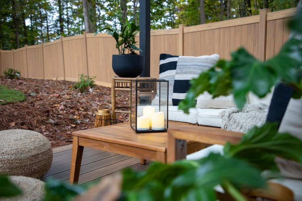 A forrested back yard with plush cushions and a nice patio.