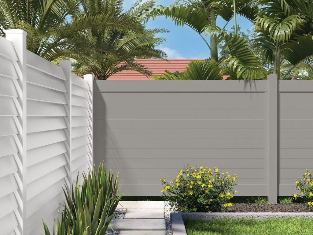 the corner of a backyard fenced in by two different styles of vinyl privacy fence.