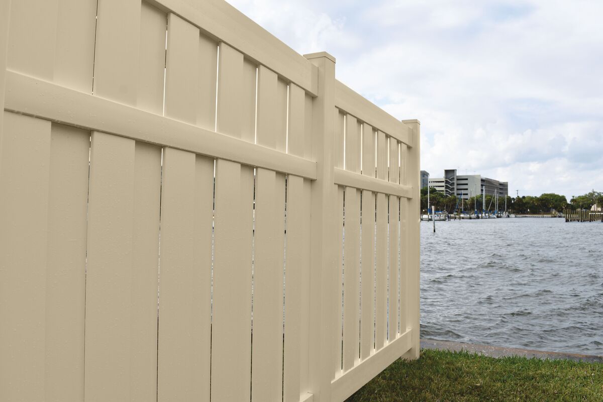 A vinyl privacy fence going down a yard in a coastal environment.