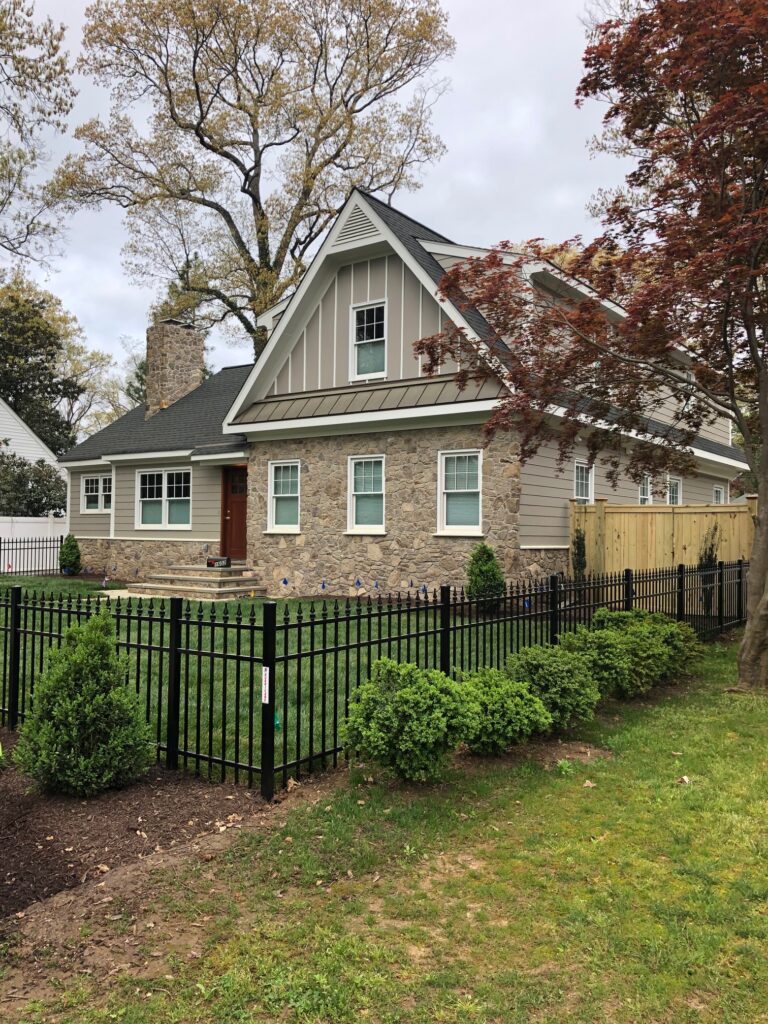 A black aluminum, four foot, picket fence surrounding a homes front yard topped with spear topped pickets.